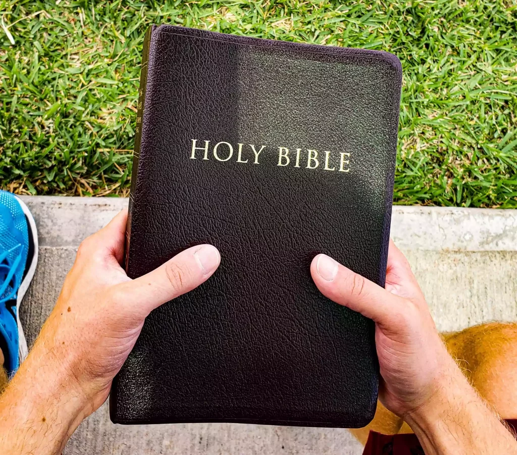 man holding bible over shoes
