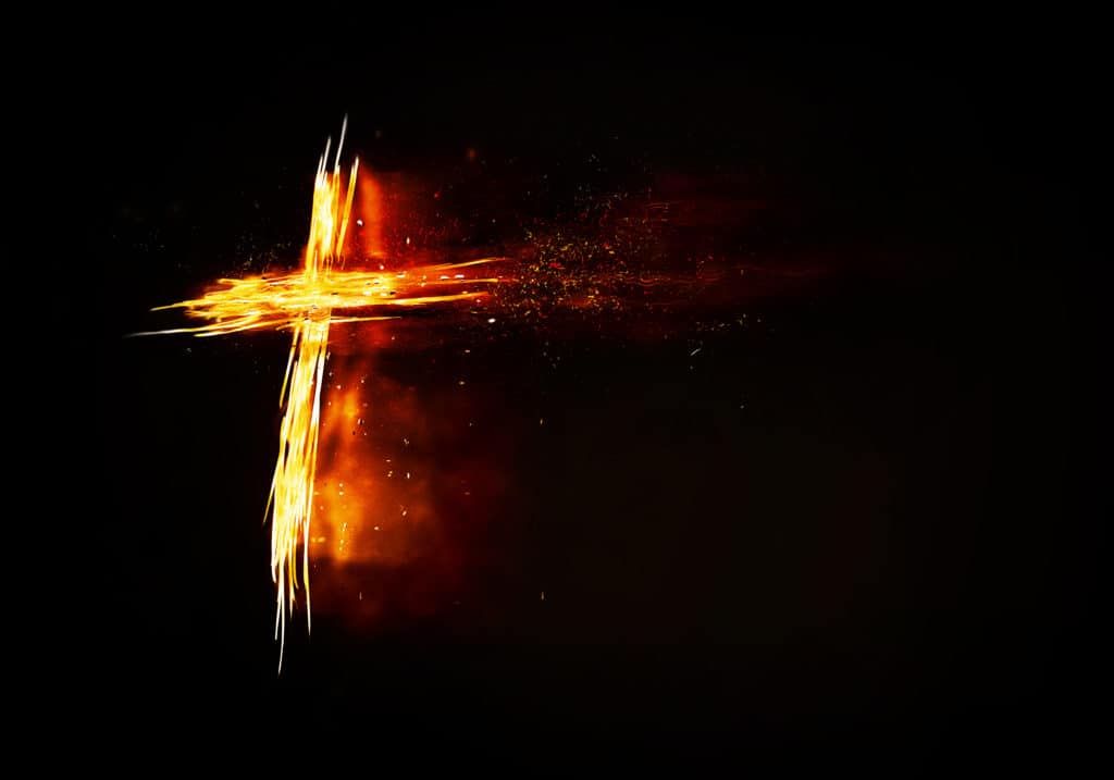 A glowing and burning cross on a black background