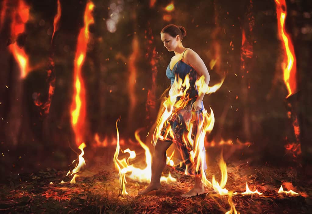 A woman walks through a burning forest fire