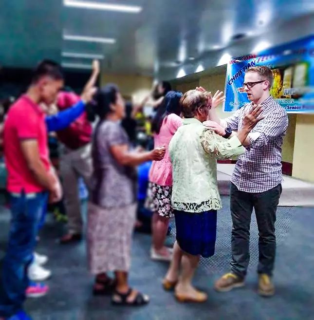 Yeshuah Boyton praying in a service for a Pilipino congregation the background is blurred out