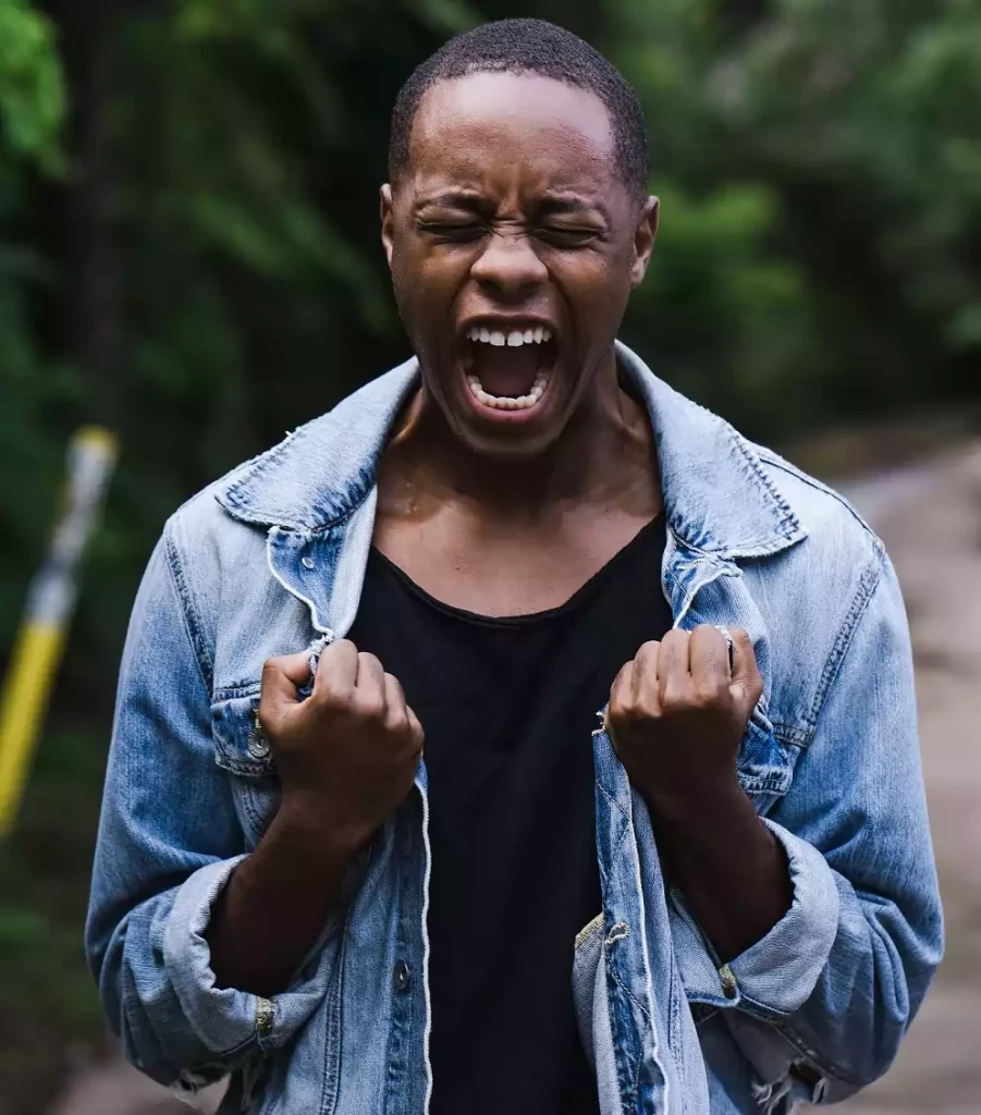 man screaming and raising both fists to his chest