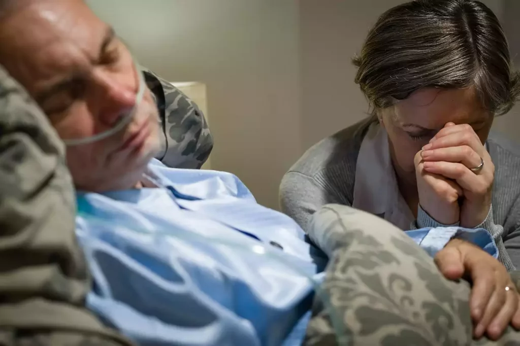 old wife praying for terminally ill husband lying in coma