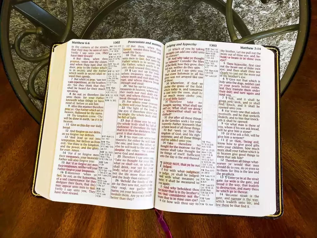 Open KJV Bible with colorful highlights on the pages laying on a wooden coffee table